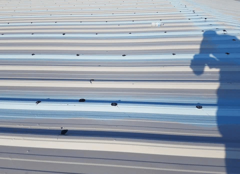 Commercial corrugated metal roof showing signs of wear, cracking, and debris—common roofing problems that require inspection and repair